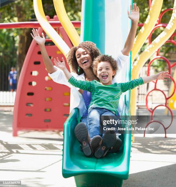 mother with son on slide at playground - kid sliding stock pictures, royalty-free photos & images