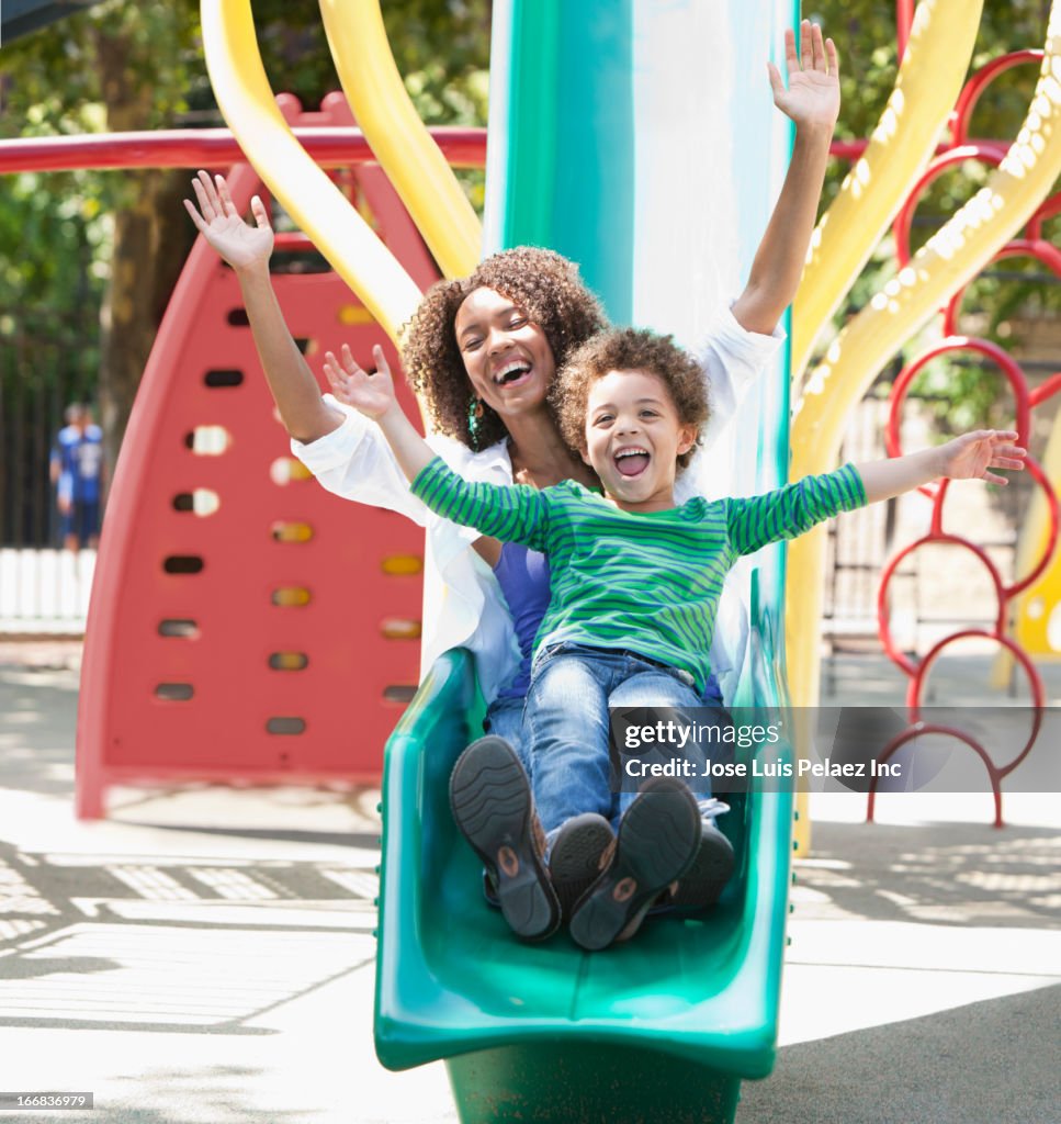 Mother with son on slide at playground