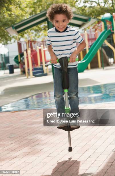 mixed race boy on pogo stick at playground - pogo stick stock pictures, royalty-free photos & images