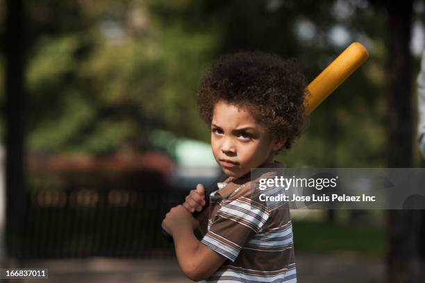 mixed race boy swinging baseball bat in park - baseball player headshot stock-fotos und bilder