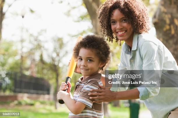 mother and son playing baseball in park - baseball player headshot stock-fotos und bilder