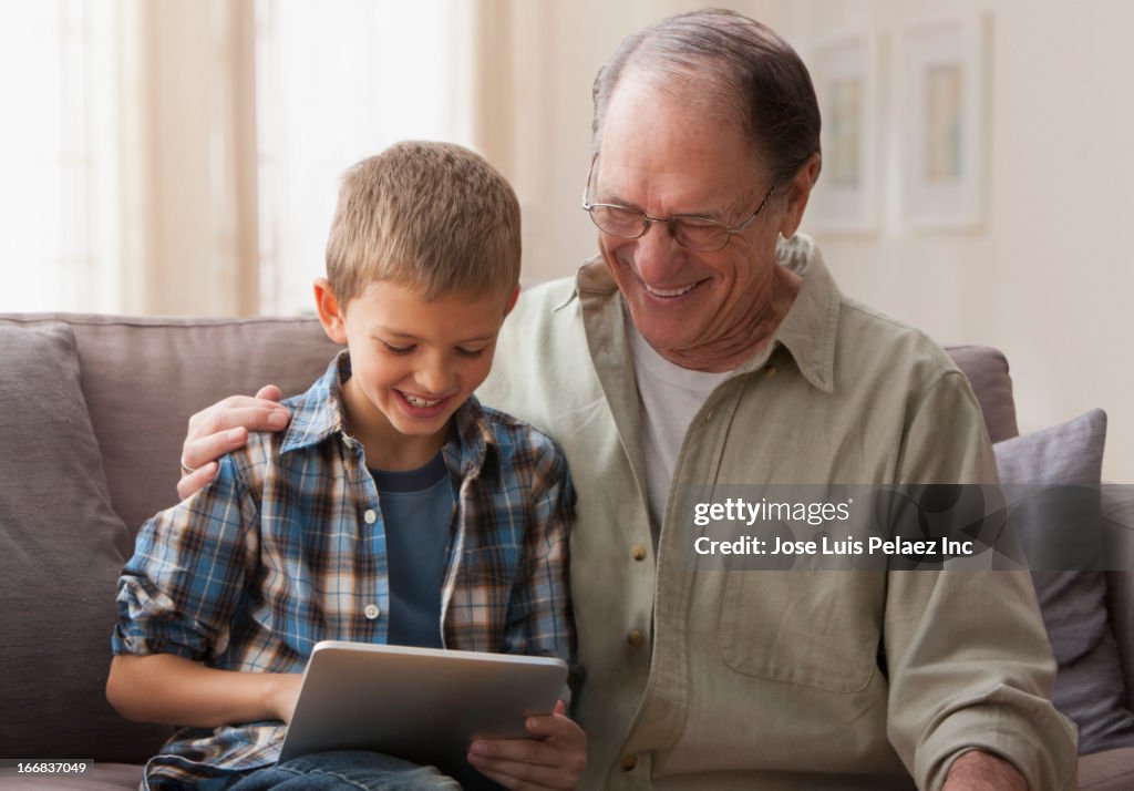 Older Caucasian man and grandson using digital tablet