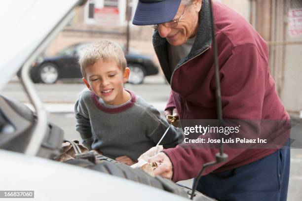 older caucasian man with grandson checking oil in car - dipstick stock pictures, royalty-free photos & images