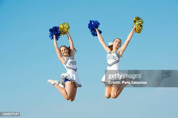 caucasian cheerleaders jumping in mid-air - pom pom stock-fotos und bilder