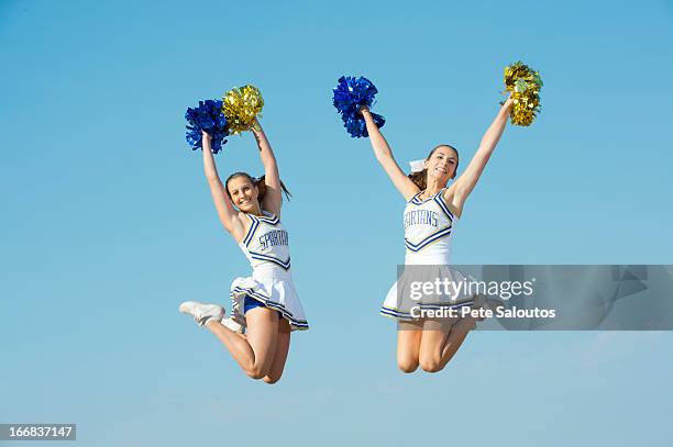 caucasian cheerleaders jumping in mid-air - チアリーダー ストックフォトと画像