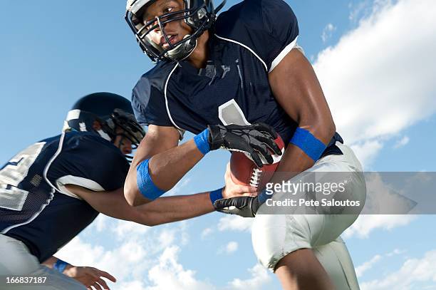 football players passing ball - high school football stockfoto's en -beelden