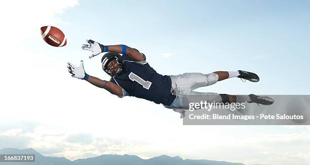 african american football player catching ball - football-spieler stock-fotos und bilder