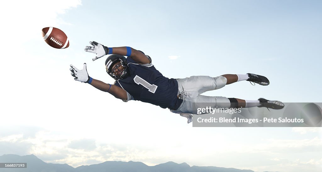 African American football player catching ball