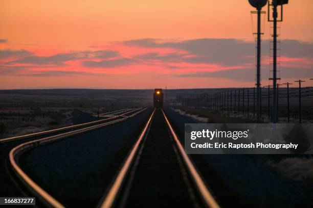 sunset over train on tracks in rural landscape - railway tracks sunset stock pictures, royalty-free photos & images