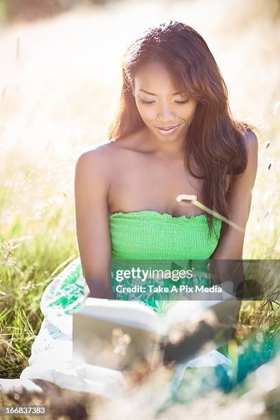 mixed race woman reading in grass -  "suprijono suharjoto" or "take a pix media" stock pictures, royalty-free photos & images