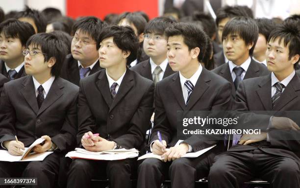 Japanese college students who will graduate in March, dressed in their traditional grey businessman suits, attend a two-day employment exhibition in...