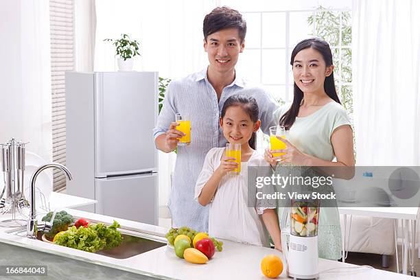family drinking juice in kitchen - fond orange fotografías e imágenes de stock
