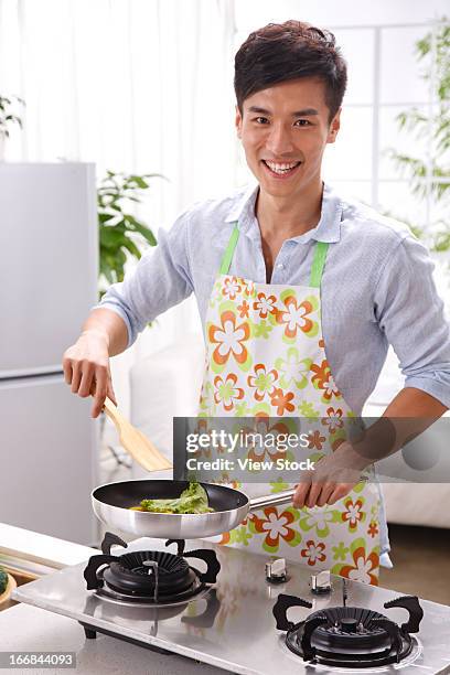 young man cooking in kitchen - huisman stockfoto's en -beelden
