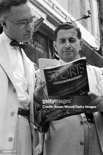 Pair of men look through the premiere issue of Sports Illustrated magazine on a Manhattan sidewalk, New York, New York, August 16, 1954.