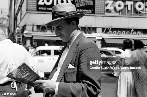 Man looks through the premiere issue of Sports Illustrated magazine on a Manhattan sidewalk, New York, New York, August 16, 1954.