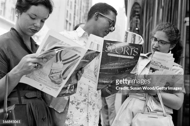 People look through the premiere issue of Sports Illustrated magazine on a Manhattan sidewalk, New York, New York, August 16, 1954.