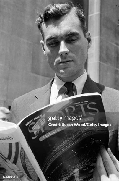 Man looks through the premiere issue of Sports Illustrated magazine on a Manhattan sidewalk, New York, New York, August 16, 1954.