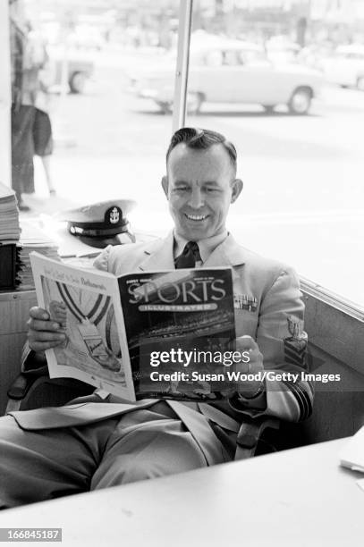 In a Manhattan shop window, a soldier smiles as he looks through the premiere issue of Sports Illustrated magazine, New York, New York, August 16,...