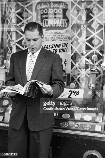 Man looks through the premiere issue of Sports Illustrated magazine on a Manhattan sidewalk, New York, New York, August 16, 1954.