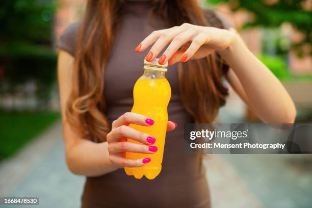 close-up woman hands opening a plastic orange bottle of lemon juice - fizzy lemonade stock pictures, royalty-free photos & images