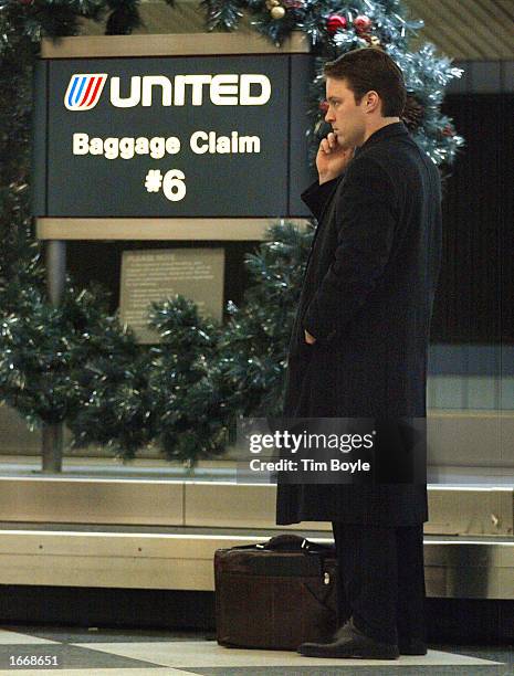 Air traveler Paul Randles of Columbus, Ohio talks on a cell phone as he waits for his luggage at the baggage claim area at the United Airlines...