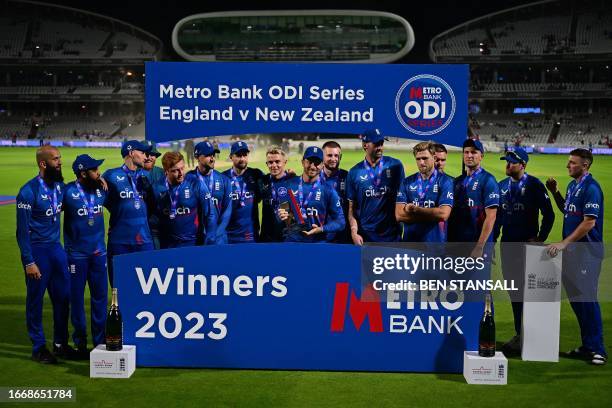 England's Jos Buttler holds the trophy as he poses with teammates after England won the fourth One Day International cricket match between England...