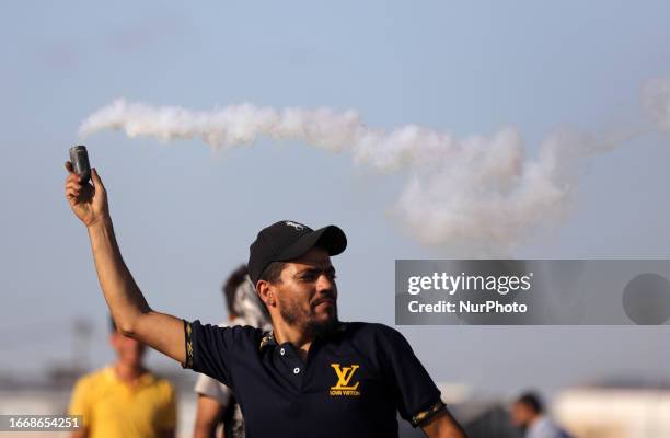 Palestinian protester holds a tear gas canister fired by Israeli forces during clashes with Israeli soldiers along the Israel-Gaza border on...
