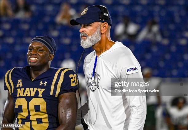 Navy Midshipmen head coach Brian Newberry helps running back Amin Hassan off the field after an injury during the Wagner Seahawks game versus the...
