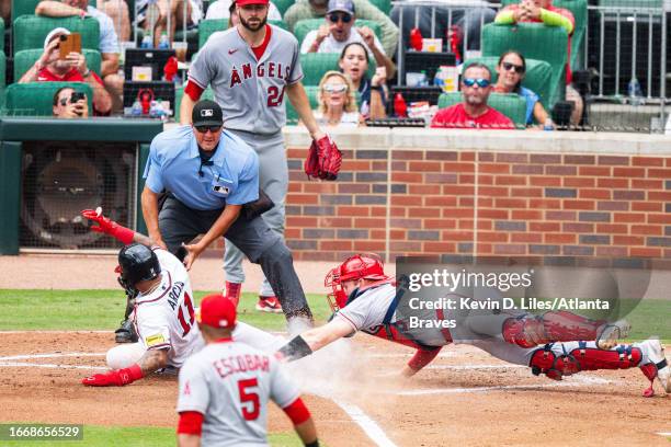 Orlando Arcia of the Atlanta Braves slides safely into home past Chad Wallach of the Los Angeles Angels during the game at Truist Park on August 02,...