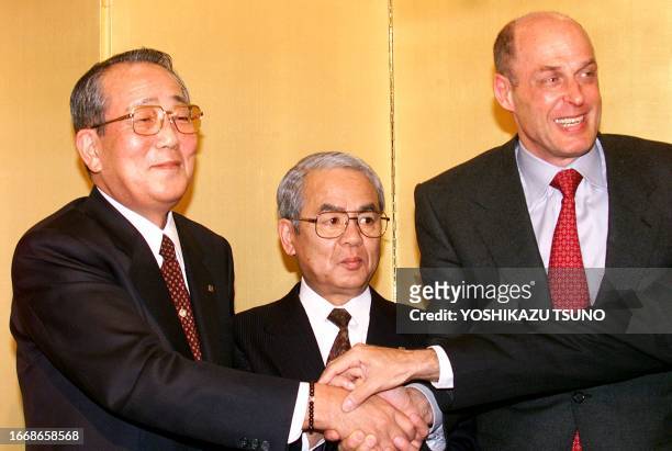 Kazuo Inamori, founder of Kyocera, Kensuke Ito, chairman of Kyocera and Henry Paulson, CEO of Goldman Sachs, join hands during a press conference to...