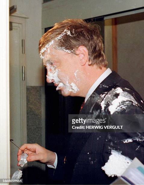 Microsoft chairman Bill Gates moves his spectacles after being hit in the face by a whipped cream pastry on his arrival at "Concert Noble" in...