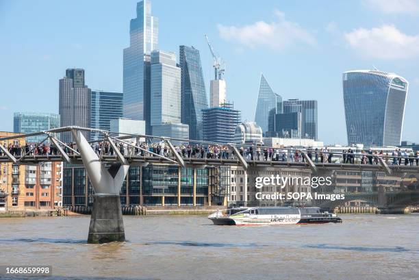 Protesters queue up in a single line on the Millennium Bridge during the demonstration. Hundreds of businesses joined 'queue for climate' on London's...