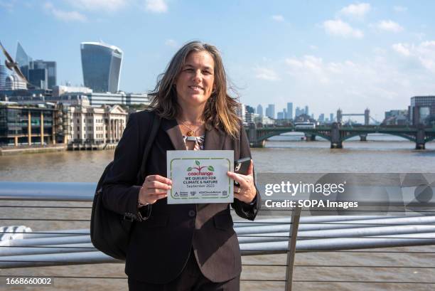 Protester poses for a photo with a placard during the demonstration on the Millennium Bridge. Hundreds of businesses joined 'queue for climate' on...