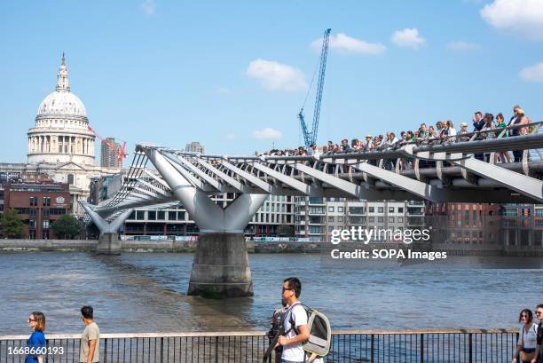 Protesters queue up in a single line on the Millennium Bridge during the demonstration. Hundreds of businesses joined 'queue for climate' on London's...