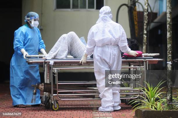 Health workers wearing protective gears shift a man with symptoms of Nipah virus to an isolation ward at a government hospital in Kozhikode in south...