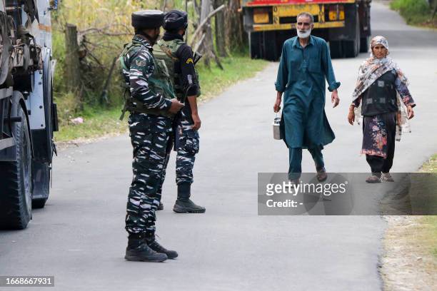 Indian army soldiers stand guard as a Kashmiri family walks past the Gadole forest of Kokernag in south Kashmir's Anantnag district on September 16,...