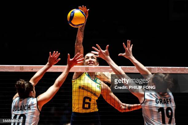 Brazil's Thaisa Daher de Menezes spikes the ball past Argentina's Daniela Bulaich Simian and Brenda Graff during the Volleyball World Cup 2023...