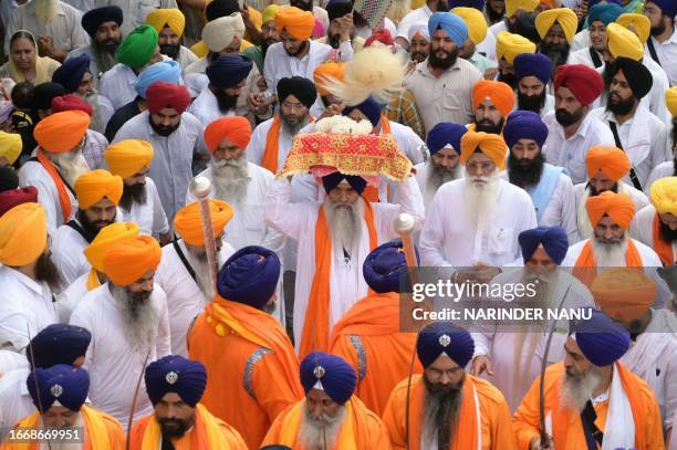 Sikh head priest Giani Raghbir Singh carries the 'Guru Granth Sahib', Sikh holy book, during a religious procession from the Gurudwara Ramsar to Akal...