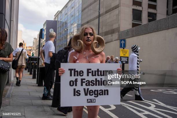 Nearly naked woman of the People for the Ethical Treatment of Animals protester dressed as a sheep holds a placard expressing her opinion outside the...