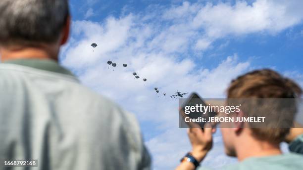 Visitors look at paratroopers performing an airborne jump in Ede on September 16, 2023 during the 79th commemoration of the airborne landing that...