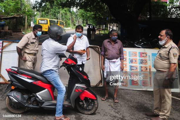 Police and health officials check the identification card of a man at a checkpoint along a road entering a containment zone following an increase of...