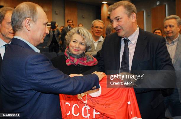 Russia's President Vladimir Putin and Soviet hockey legend, goalkeeper Vladislav Tretiak , hold a USSR hockey team 's jersey before watching the...