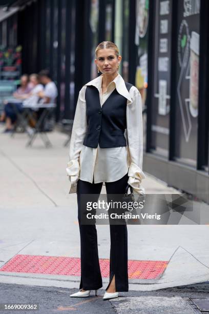 Xenia Adonts wears black vest, white button shirt, pants with slit, Dior bag outside Helmut Lang on September 08, 2023 in New York City.