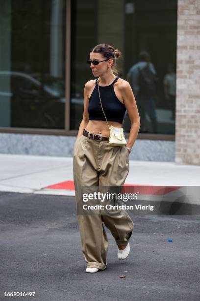 Guest wears cropped top, beige mini bag, khaki pants outside Helmut Lang on September 08, 2023 in New York City.