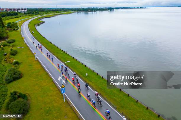 Cyclists celebrate with champagne on the podium during the 2023 11th Round Taihu International Road Cycling Race in Dianshanhu town, Kunshan city,...