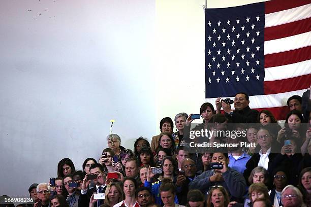 People watch as President Barack Obama speaks to runners and Boston Marathon volunteers at Cathedral High School after attending an interfaith prayer...