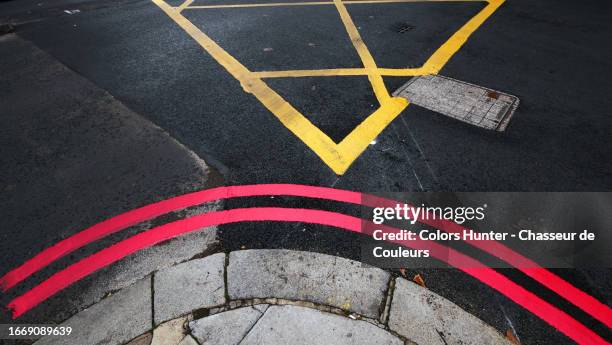 two parallel red lines painted on the tarmac of a street and at the edge of a sidewalk in london, england, united kingdom - road marking stock pictures, royalty-free photos & images