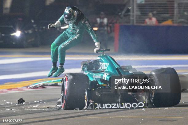 Aston Martin's Canadian driver Lance Stroll jumps out of his car after crashing during the qualifying session of the Singapore Formula One Grand Prix...