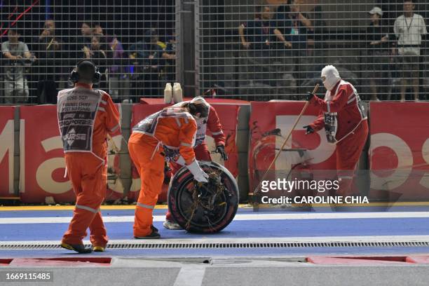 Track workers clean up debris after Aston Martin's Canadian driver Lance Stroll crashed his car during the qualifying session of the Singapore...