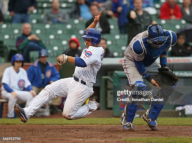 Welington Castillo of the Chicago Cubs slides in to score a run in the 5th inning as A.J. Pierzynski of the Texas Rangers drfops the ball at Wrigley...